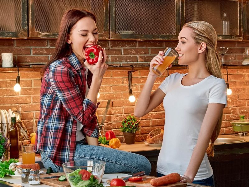 eat-well-to-be-well-young-female-friends-preparing-together-healthy-meal-in-modern-kitchen-cozy-1.jpg